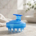 Blue silicone scalp massager with T-handle in a bright bathroom