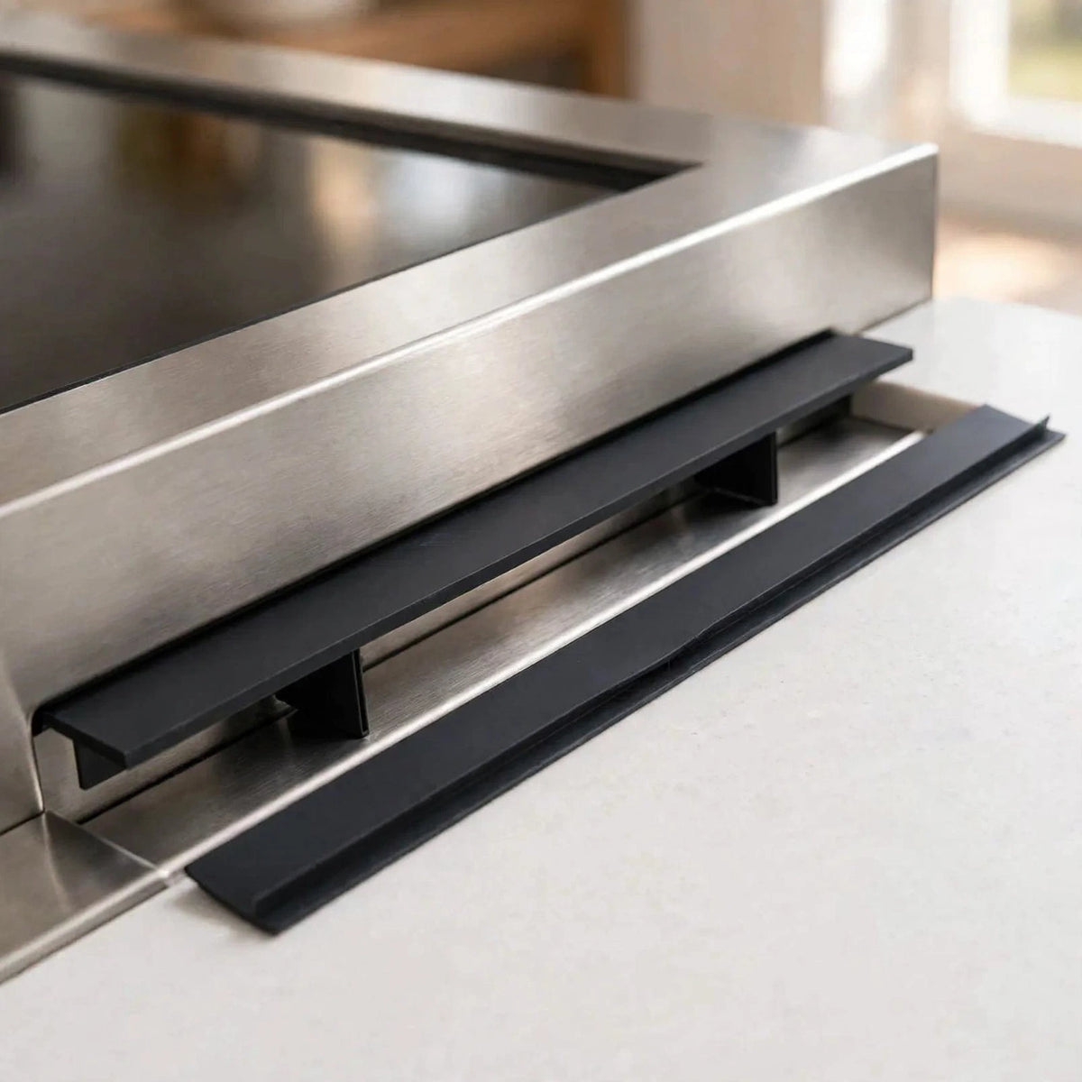 Black silicone stove gap covers installed between a stove and countertop